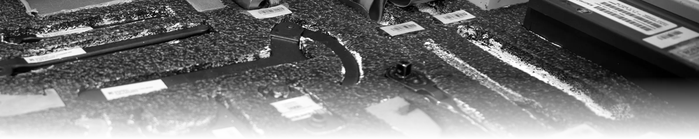 A labelled foam shadow-board tool drawer in a military aircraft maintenance tool crib, each wrench and tool set into its own cut-out slot with a barcoded accountability tag