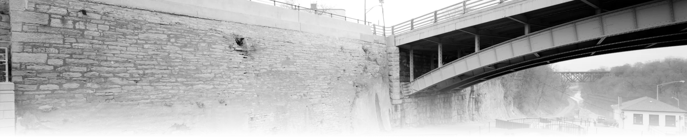 A black-and-white HAER photograph of the Lockport Locks on the New York State Barge Canal, showing a stacked stone lock wall and an arching road bridge crossing the lock cut