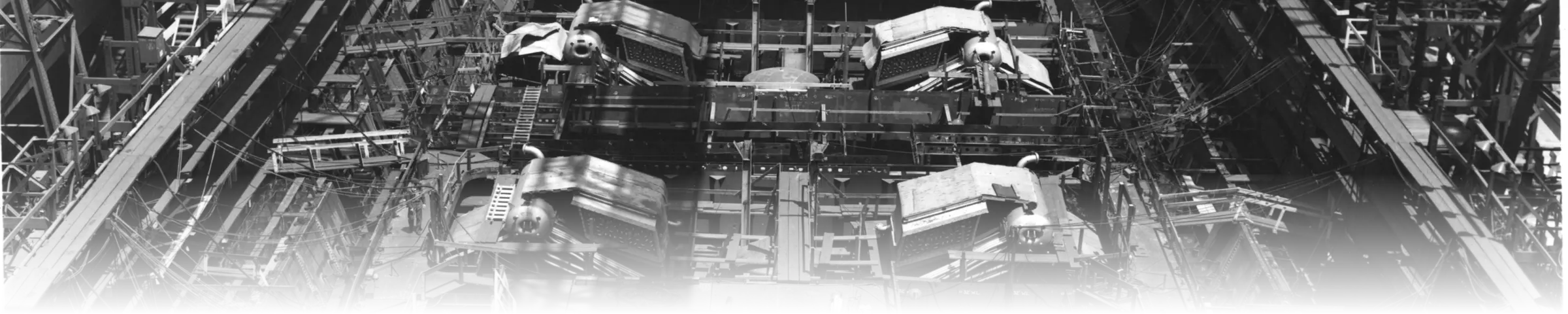 The battleship USS Iowa under construction on the building ways at the New York Navy Yard in 1941, viewed down the length of the hull with turret barbette machinery being fitted inside the framed structure.