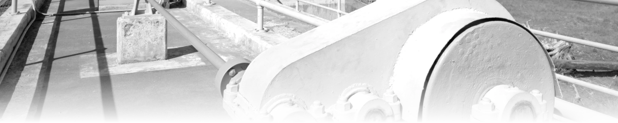 A black-and-white photograph of the radial-gate hoist mechanism and walkway railings on the spillway bridge at Kachess Dam