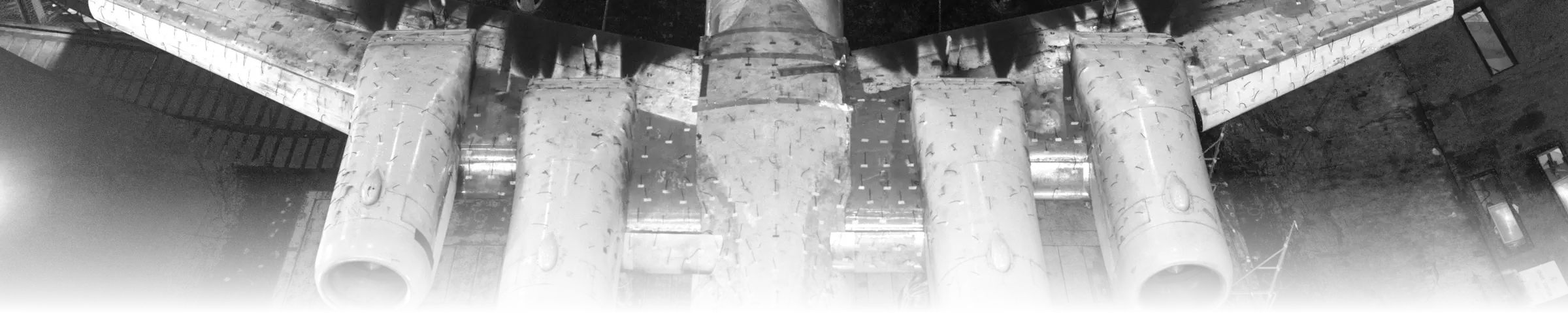 A four-engine wind-tunnel test model, mounted from below in a full-scale tunnel, its wing and engine nacelles filling the frame edge to edge