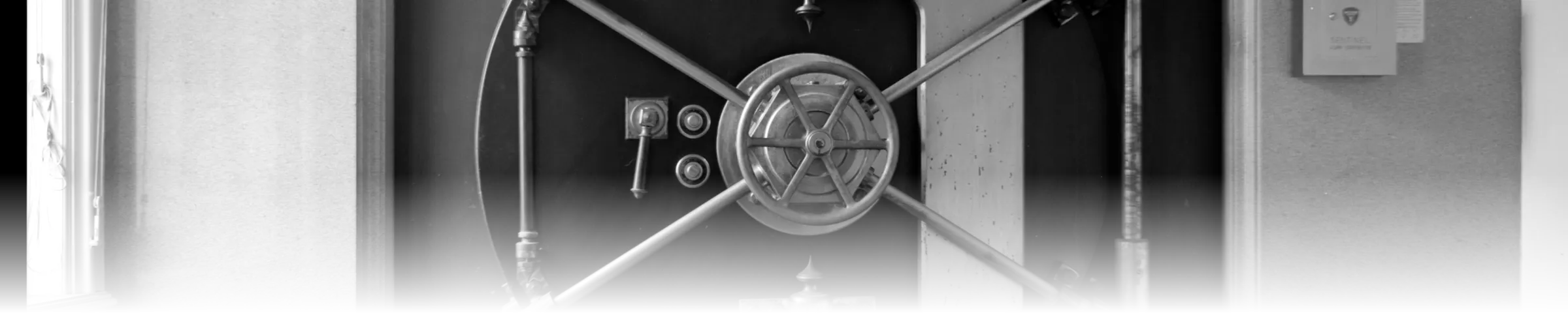 A historic walk-in bank vault door photographed square-on, its diagonal bolt-throw bars crossing over a central combination wheel