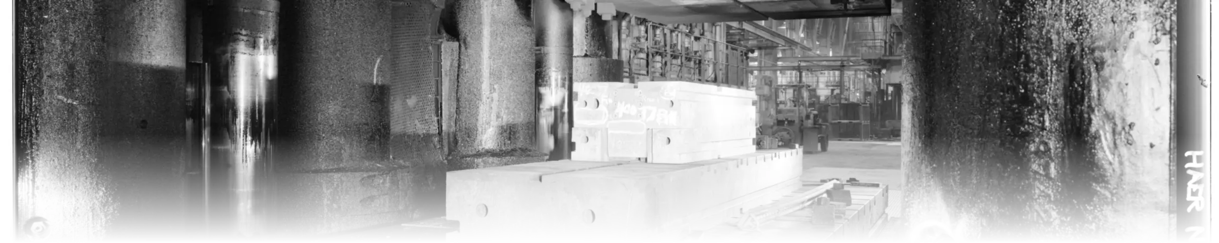 A black-and-white photograph of a machined forging die, tagged "MOD 17FM", seated in the bed of a large industrial closed-die forging press