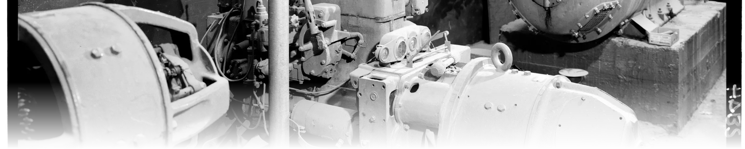 A black-and-white photograph of two diesel generator units in a private power house, dense with engine block, gauge cluster, and generator housings