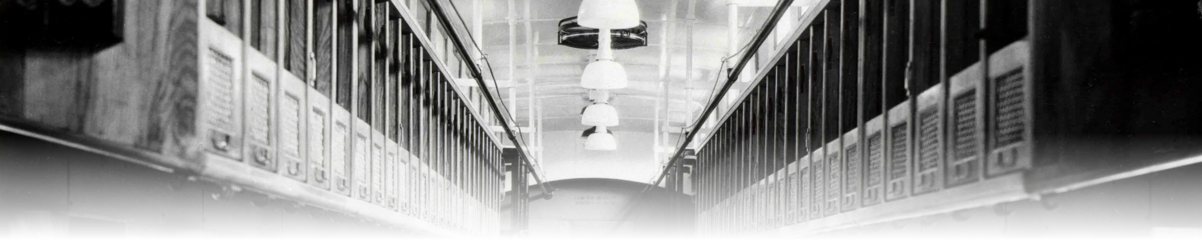 A black-and-white 1905 photograph of the interior of a Railway Post Office car, showing two facing walls of individually labelled pigeonhole mail-sorting racks lining a narrow aisle
