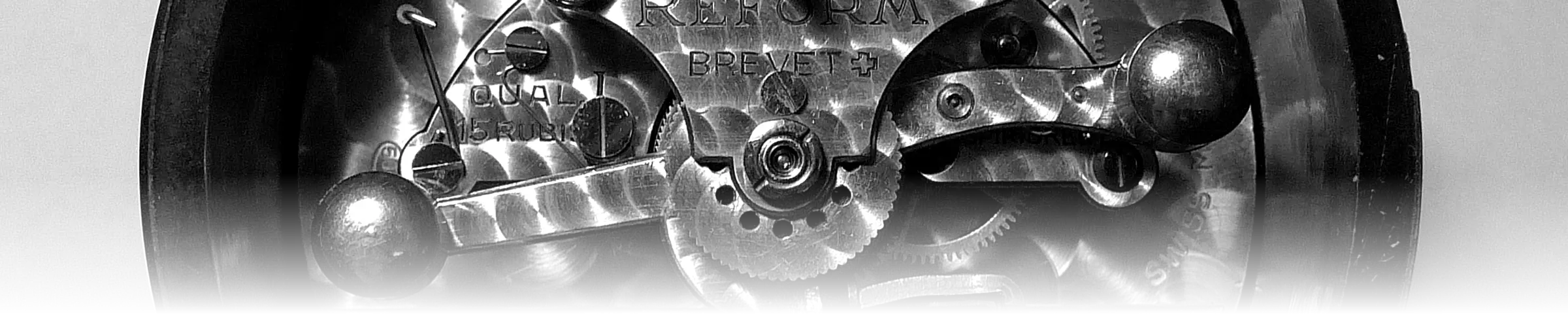 The exposed movement of a mechanical clock, showing its balance wheel, gear train, and engraved regulator plate